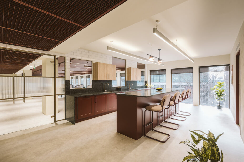 Staff kitchen and breakout bar area inside the Cannon Green office fit-out, with bar stools and wood cabinetry