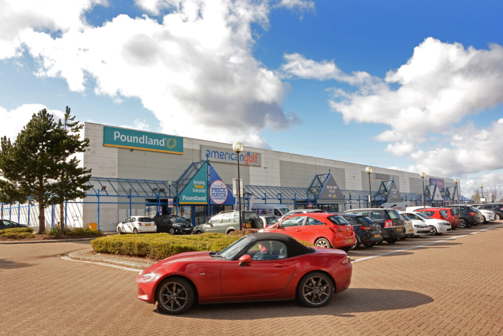 Poundland and American Golf store fronts with parked cars at The Place Retail Park