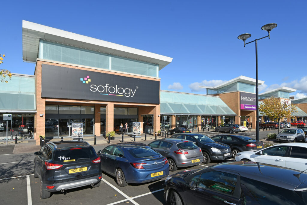 Sofology and Harveys store fronts with parked cars at Abbotsinch Shopping Park