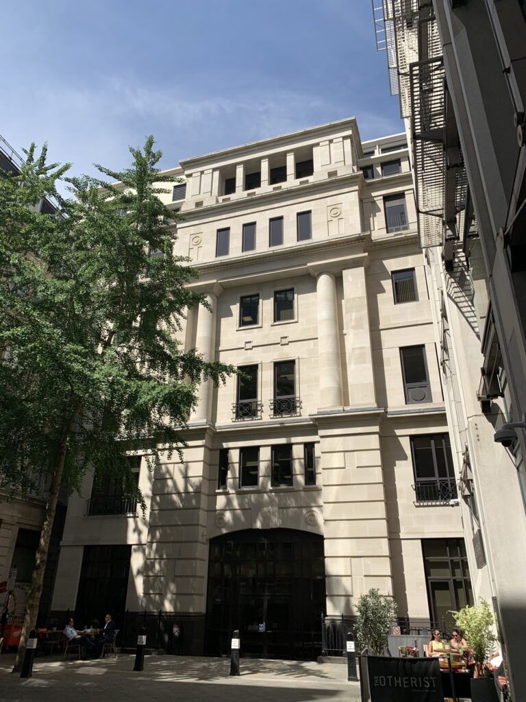 Courtyard entrance to Pinners Hall with a tree and outdoor seating in front of the building