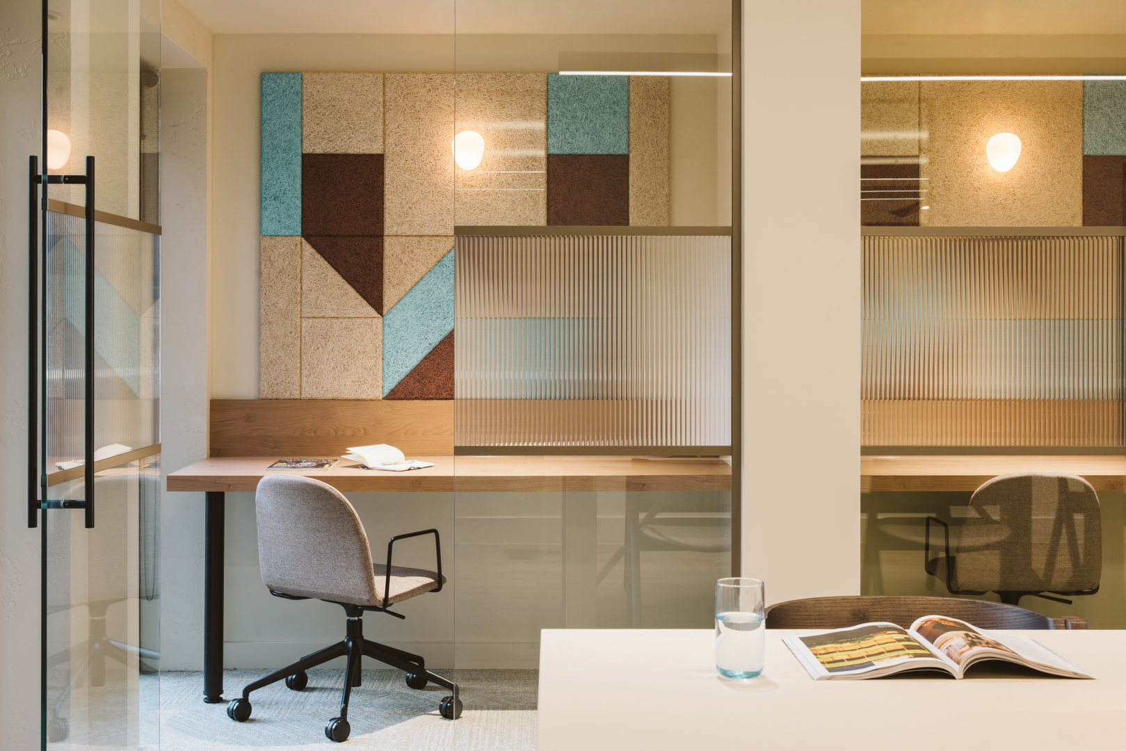 Open-plan office space at Cannon Green with a patterned acoustic panel wall, workstations and glazed meeting rooms