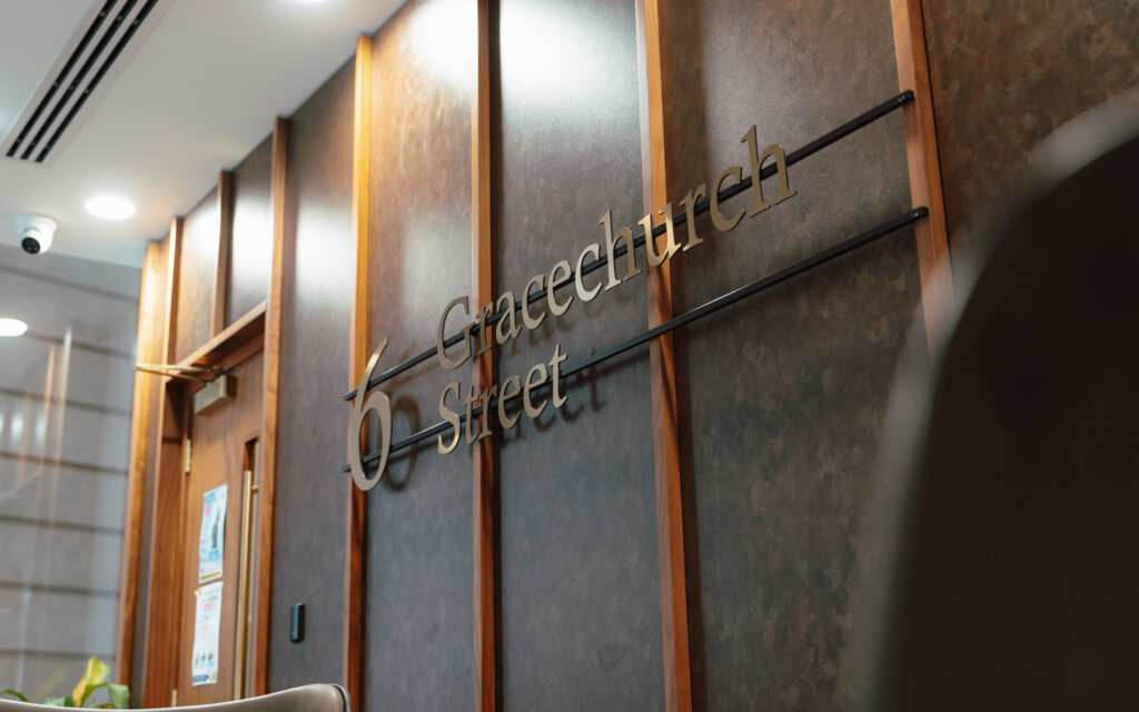 Reception at 6 Gracechurch Street, with timber panelling, lounge chairs and a curved desk
